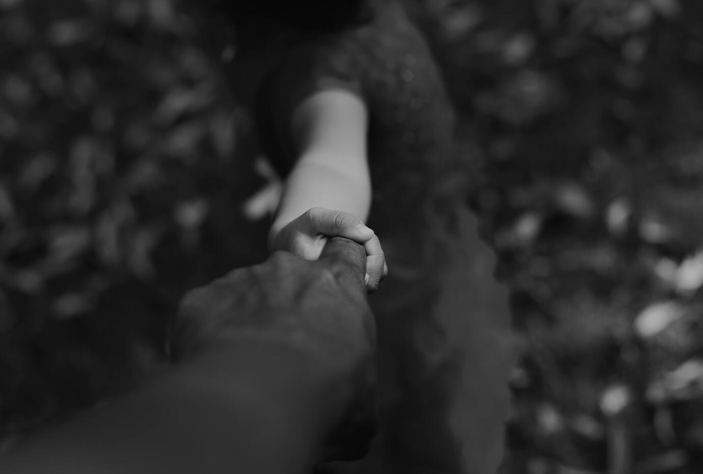 Guided by love and trust — walking into the future together Black and white photo of one person leading another by the hand, symbolizing guidance and trust